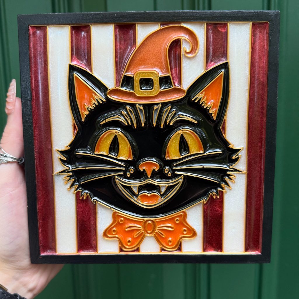 an artwork containing a vintage Halloween style black cat with a hat and bowtie. the artwork has a white and red striped background.