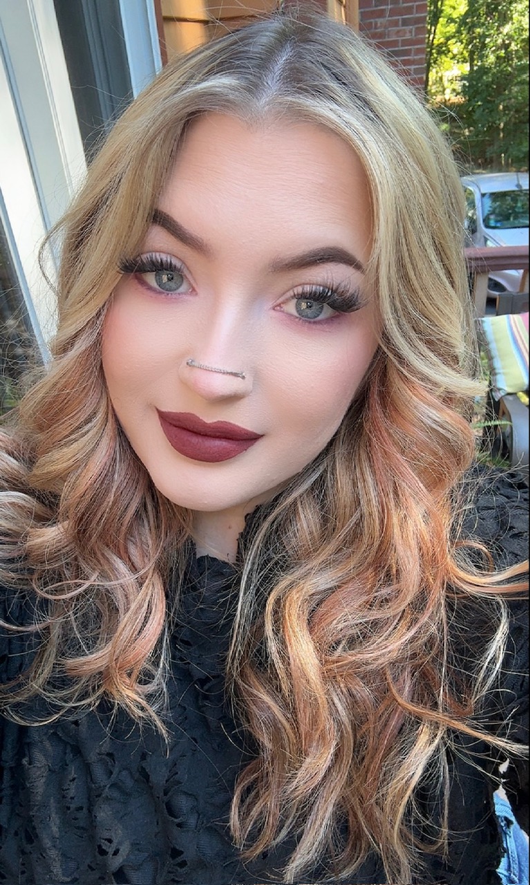 a photo of a girl with long blonde and red hair . she has brown lipstick and long eyelashes.